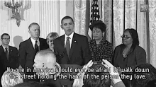 a group of people standing around a podium with the words " no one in america should ever be afraid to walk down the street "