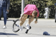 a man in a pink shirt is falling off his bike