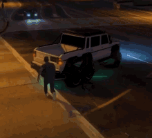 a man is standing next to a white truck that is parked on the side of the road at night