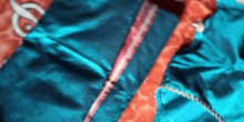 a close up of a blue and orange fabric with a red stripe on the bottom