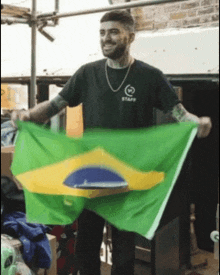 a man in a staff shirt holds up a green and yellow flag