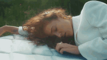 a woman with red hair is laying on a blue blanket with her eyes closed