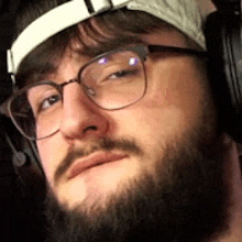 a man with a beard and glasses is wearing headphones .