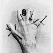 a black and white photo of a person 's hand with nails and a razor blade on it