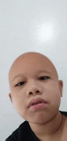 a close up of a person 's face with a bald head and a black shirt .