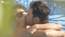 a man is kissing a woman on the forehead in a pool .