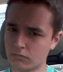 a close up of a young man 's face making a funny face while sitting in a car .