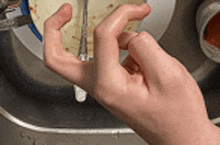 a person is washing a plate with a fork in the sink .