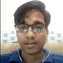 a man wearing glasses and headphones is sitting on a couch .