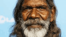 a man with long hair and a white beard is smiling for the camera .