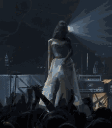 a woman in a white dress is standing on a stage