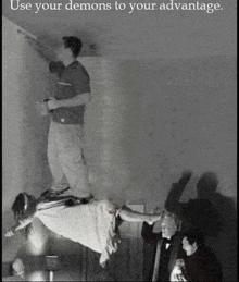 a black and white photo of a man painting a wall with a woman flying in the air .