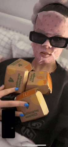 a woman with a mask on her face is holding a stack of mcdonald 's chicken nuggets