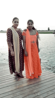 two women standing next to each other on a dock by the water