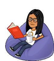 a woman is sitting on a bean bag chair reading a book and holding a cup of coffee