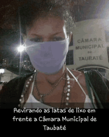 a woman wearing a mask stands in front of the camara municipal de taubate building