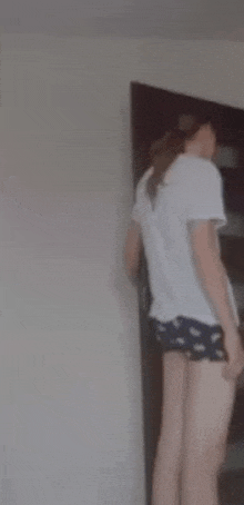 a woman in shorts is standing in front of a door .