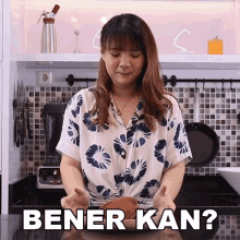 a woman in a floral shirt is standing in front of a kitchen counter with the words bener kan written on it