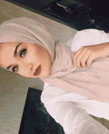 a woman wearing a white shirt and a beige hijab