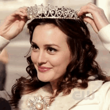 a woman is putting on a tiara on her head .