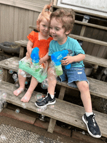 a boy and a girl are playing with soap bubble guns