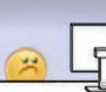 a yellow smiley face is sitting next to a computer monitor .