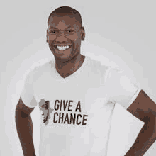 a man wearing a white t-shirt with the words `` give a chance '' on it is smiling .