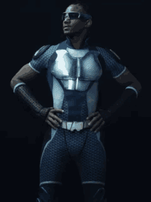 a man in a superhero costume is standing with his hands on his hips in front of a black background .