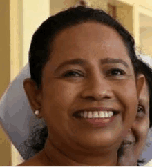 a woman is smiling for the camera and wearing a white nurse 's hat .