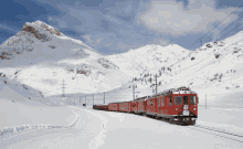 a red train is going down a snow covered road