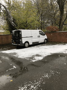 a white van is parked in a parking lot with snow on it