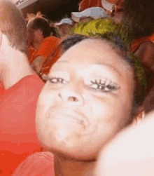 a woman with green hair is sitting in a crowd of people making a funny face .