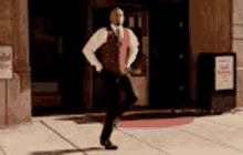 a man in a suit and tie is dancing in front of a building .