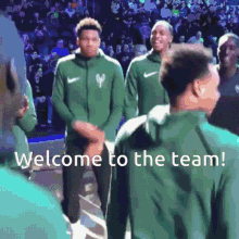 a group of basketball players are standing in front of a crowd with the words welcome to the team below them