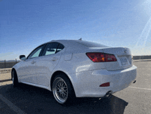 a white lexus is parked in a parking lot with a blue sky