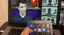 a person holding a stream deck in front of a laptop screen