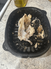 a black plastic container filled with chicken bones on a counter