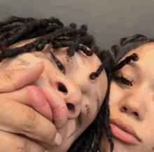 a man and a woman with dreadlocks are laying next to each other and making a face .