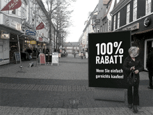 a woman stands in front of a sign that reads 100 % rabatt