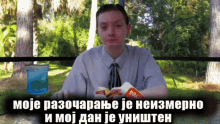 a man in a suit and tie is sitting at a table with a hamburger and a glass of water