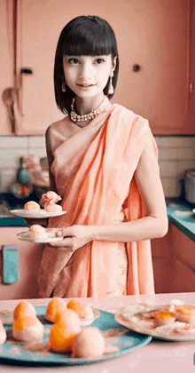 a woman in a pink dress holds plates of food