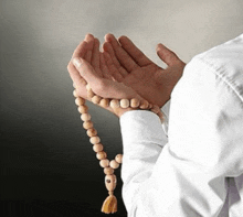 a man in a white shirt is praying with a wooden rosary