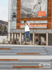 a man is jumping in the air in front of a building that has a sign that says discover more