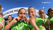 a group of female soccer players are posing for a picture in front of a banner that says deutsche meisterschaft