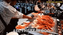 a woman is reaching for a crab leg in a buffet line with the words all the seafood above her