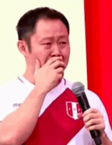 a man is crying while holding a microphone and wearing a peru shirt .