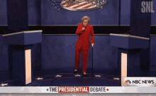 a woman in a red suit is standing in front of a podium with the presidential debate written on it