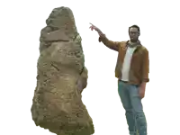 a man pointing at a large rock with his finger