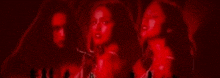 three women are standing next to each other in a dark room with red lights behind them .