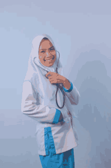 a woman with a stethoscope around her neck smiles at the camera